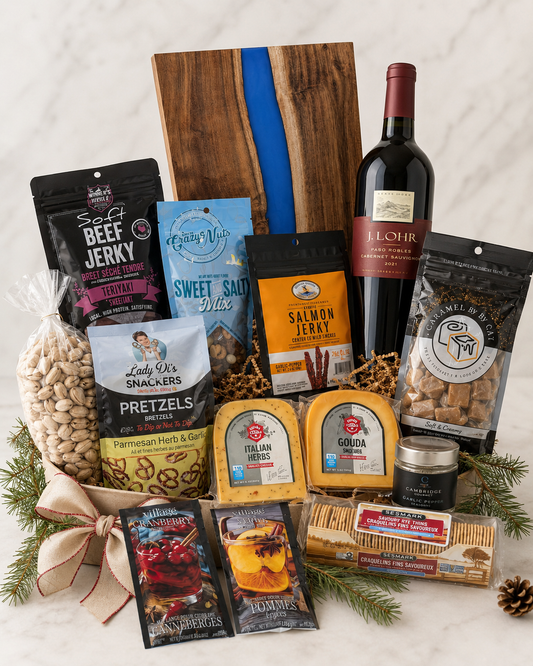 A gourmet gift basket filled with snacks, cheeses, crackers, and a bottle of red wine, arranged on a white marble surface with pine branches, a wooden board, and a ribbon bow.