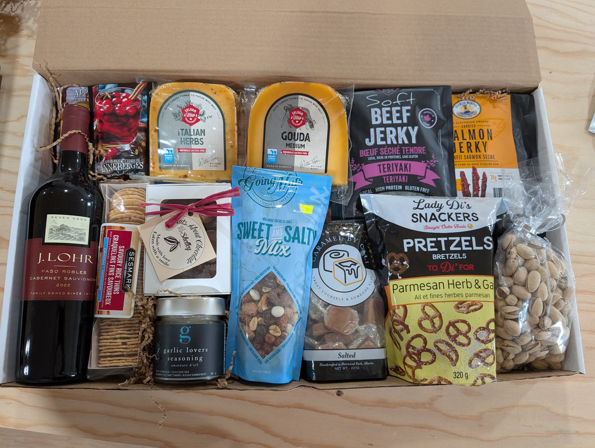 A curated gourmet gift box filled with an assortment of snacks, cheeses, crackers, and a bottle of wine.