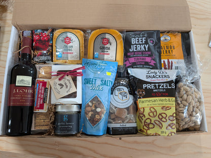 A curated gourmet gift box filled with an assortment of snacks, cheeses, crackers, and a bottle of wine.